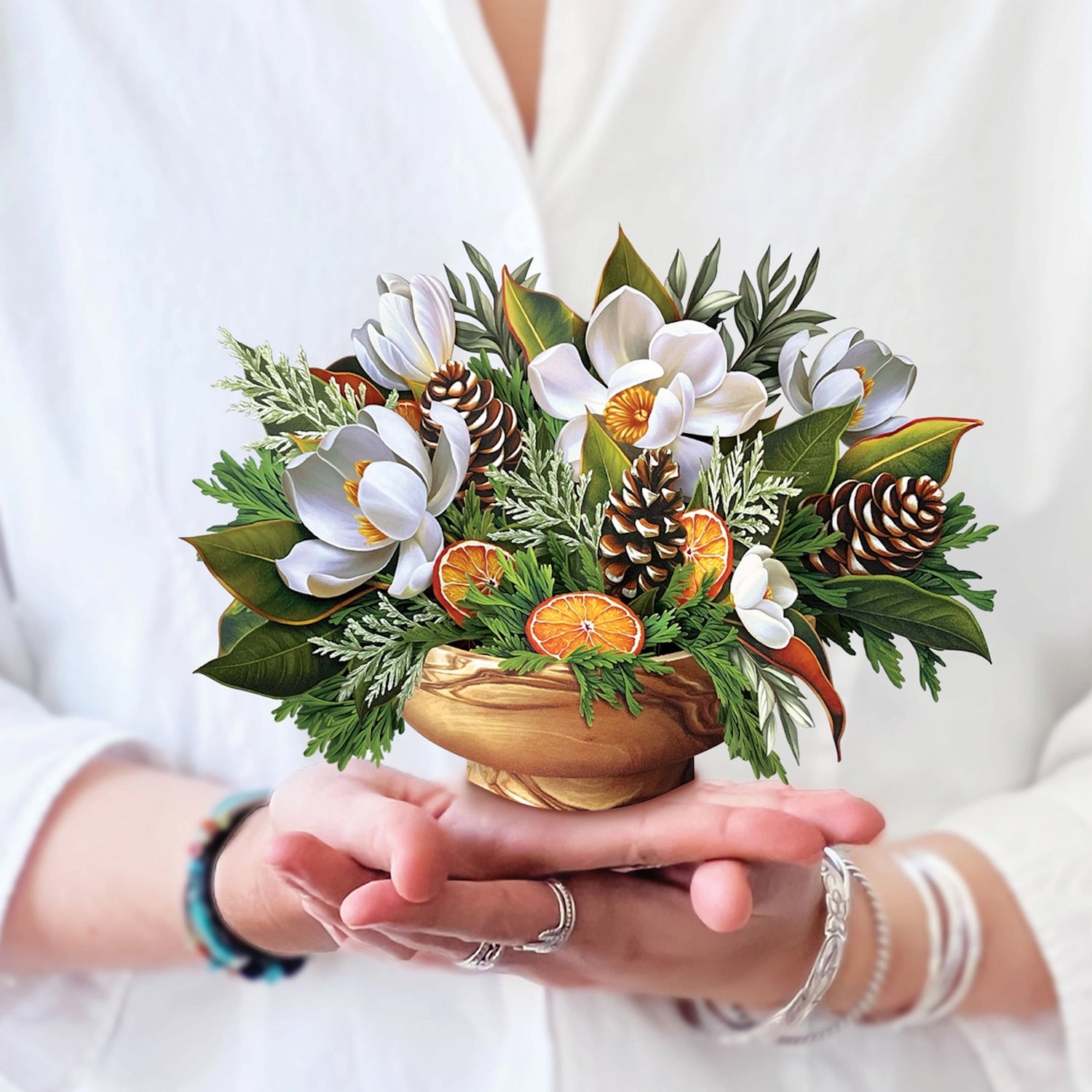 Bouquet of flowers and decorative elements held in hands against a white background