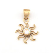 Gold sun-shaped pendant with a clear gemstone on a white background