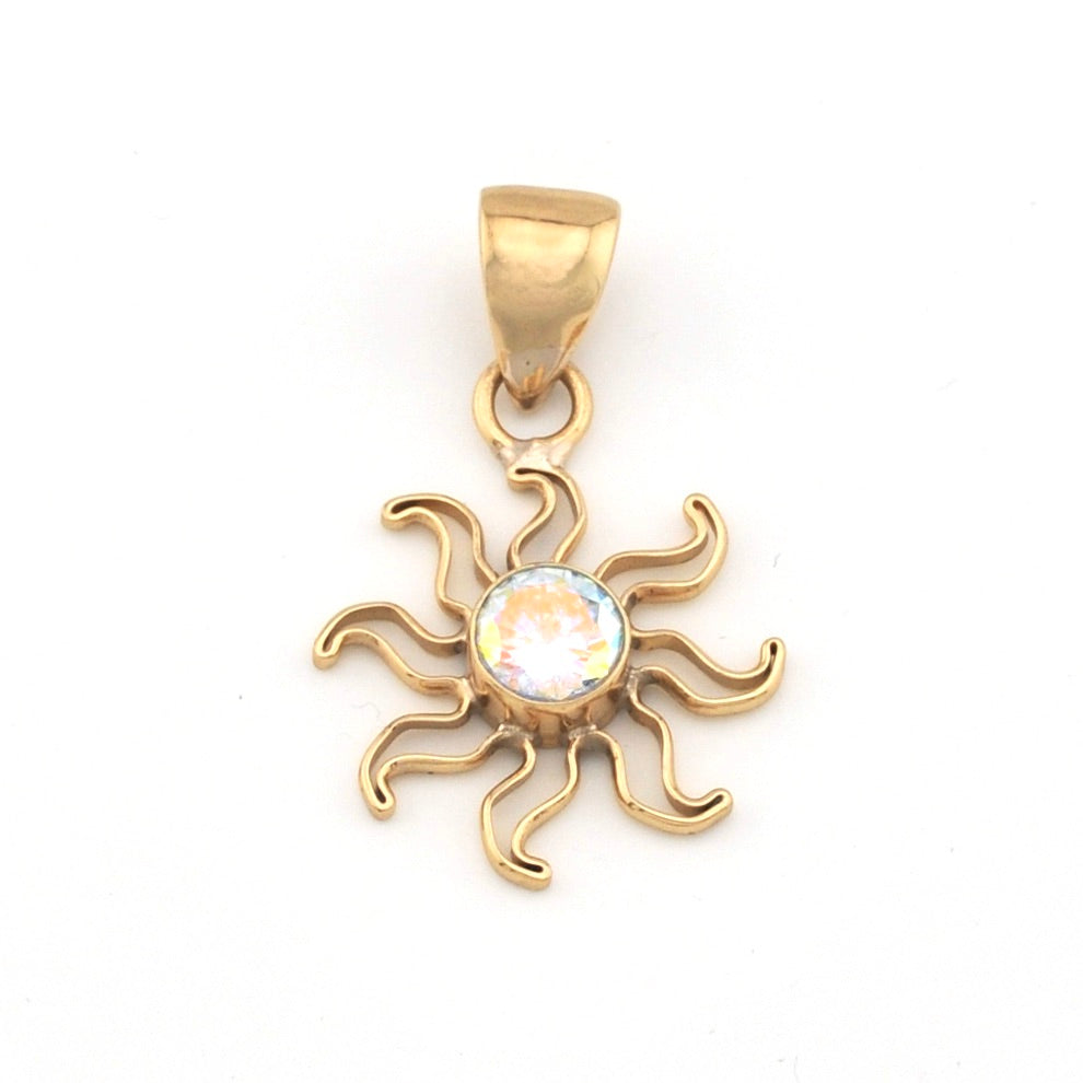Gold sun-shaped pendant with a clear gemstone on a white background