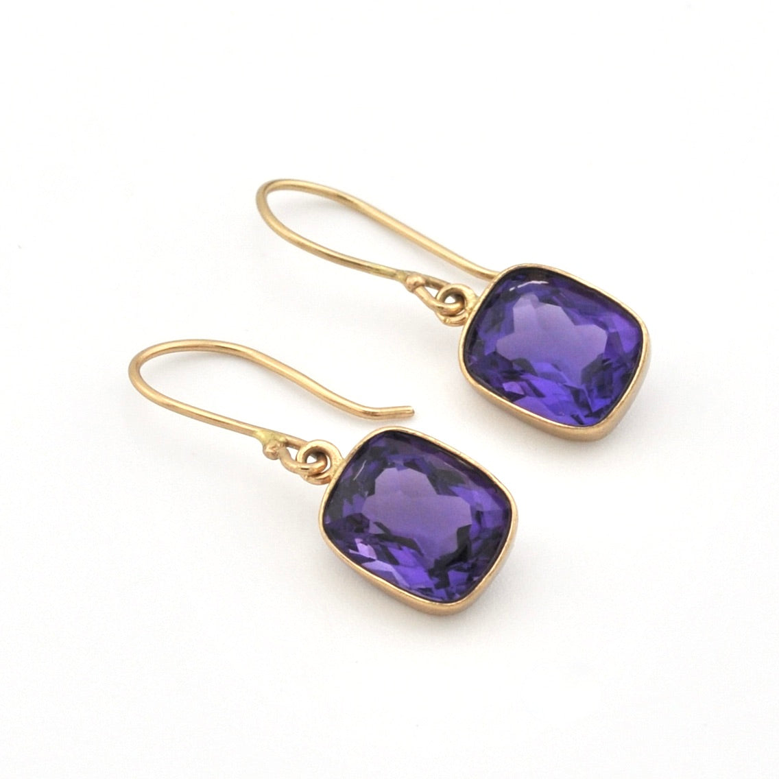 Gold earrings with purple gemstones on a white background
