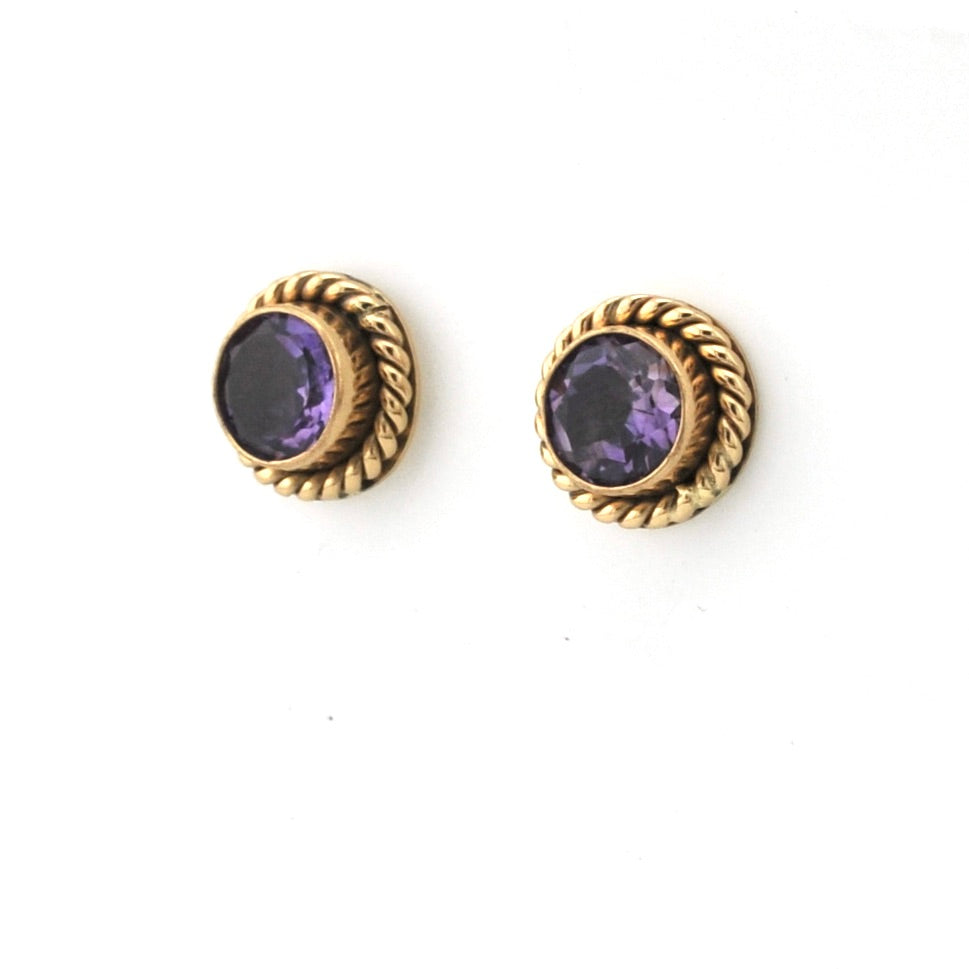 Gold earrings with purple gemstones on a white background