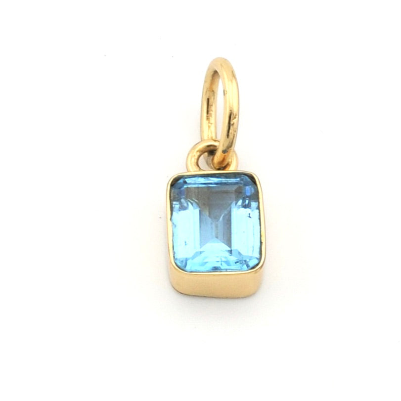 Gold pendant with a blue gemstone on a white background