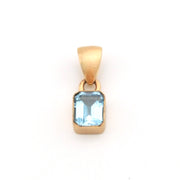 Gold pendant with a blue gemstone on a white background