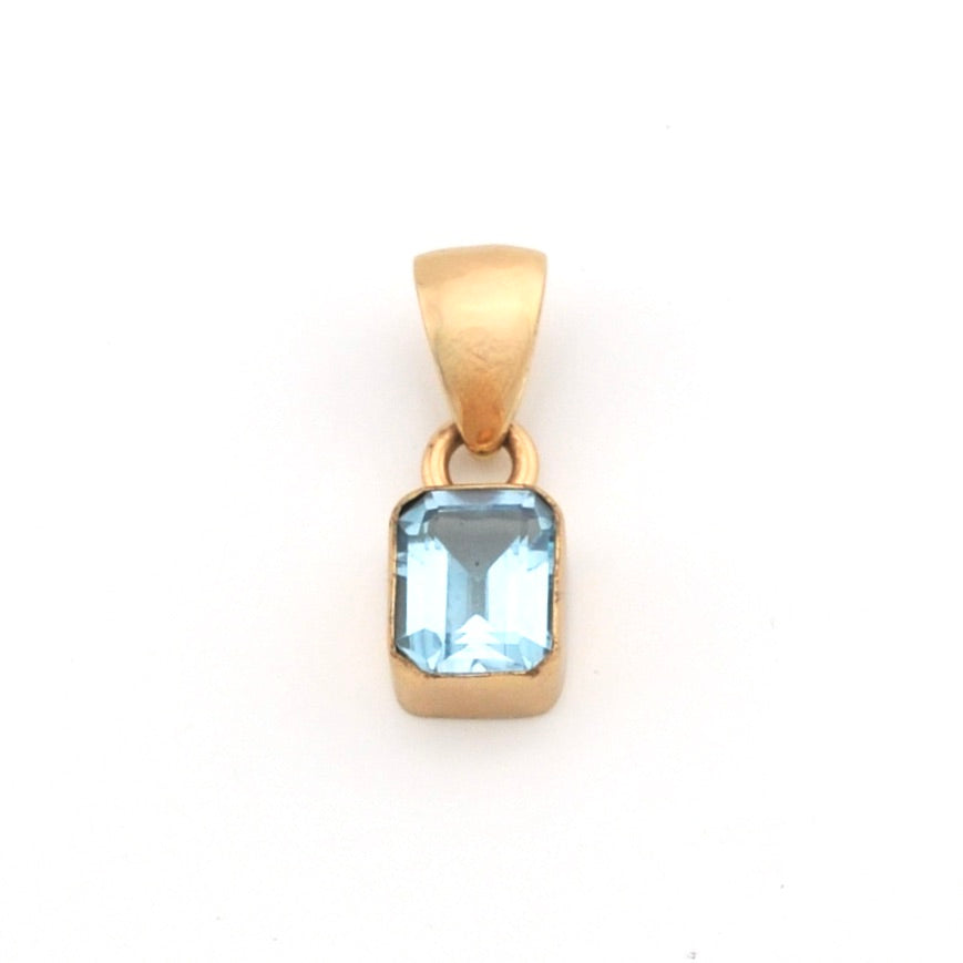 Gold pendant with a blue gemstone on a white background