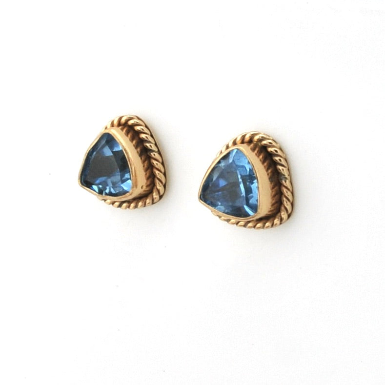 Gold earrings with blue gemstones on a white background
