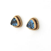 Gold earrings with blue gemstones on a white background