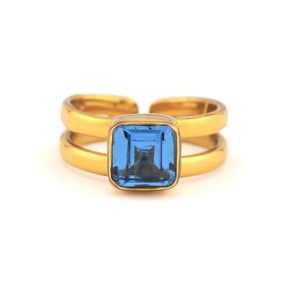 Gold ring with a blue gemstone on a white background