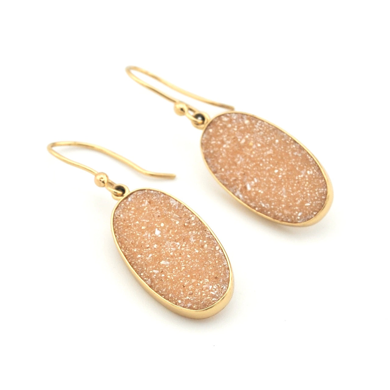 Pair of gold earrings with beige stone-like pendants on a white background