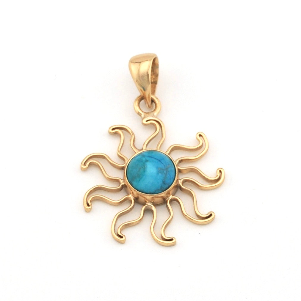 Gold sun-shaped pendant with a blue gemstone on a white background