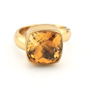 Gold ring with a large yellow gemstone on a white background