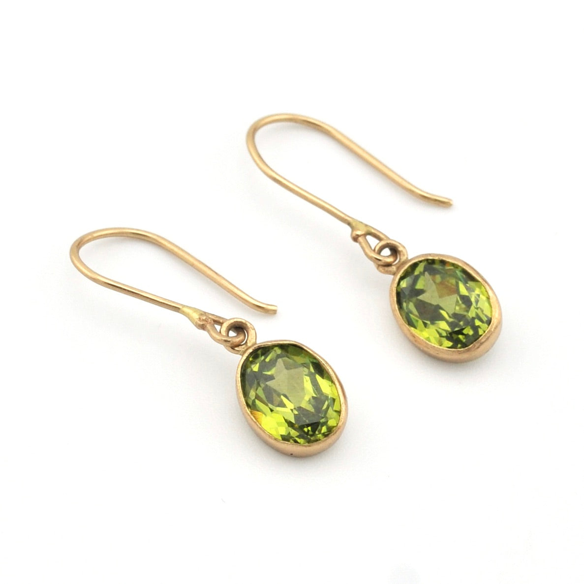 Gold earrings with green gemstones on a white background