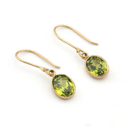Gold earrings with green gemstones on a white background