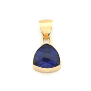 A gold pendant featuring a faceted, teardrop-shaped deep blue gemstone, set in a polished gold bezel with a matching gold bail, shown on a plain white background.