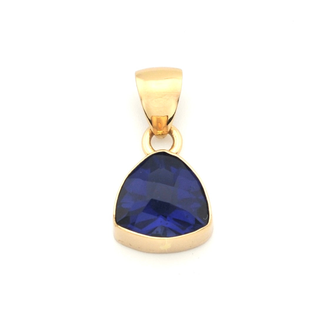 A gold pendant featuring a faceted, teardrop-shaped deep blue gemstone, set in a polished gold bezel with a matching gold bail, shown on a plain white background.