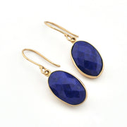 Gold earrings with blue stones on a white background