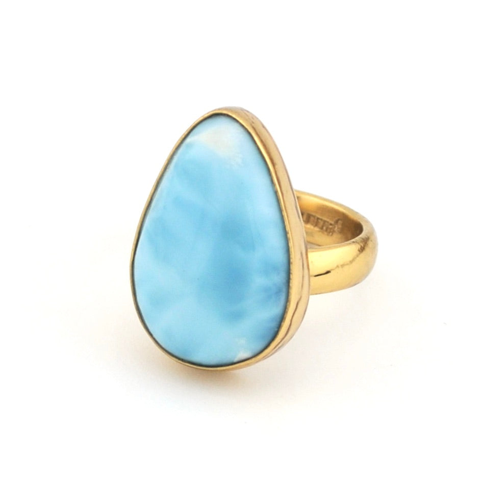 Ring with a large blue stone and gold band on a white background