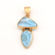 Gold pendant with two blue larimar stones on a white background