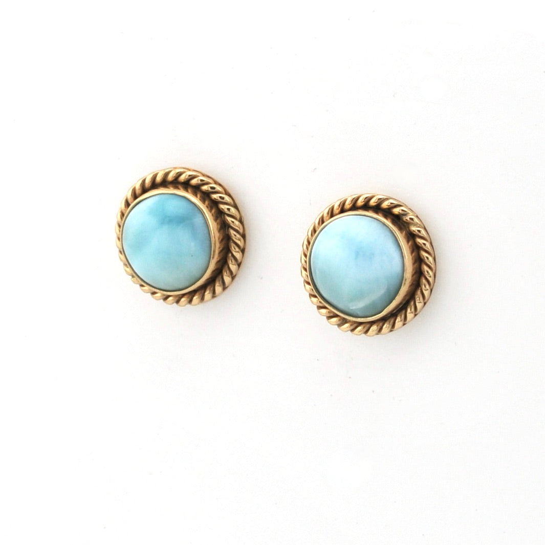 Pair of earrings with gold rims and light blue gemstones on a white background