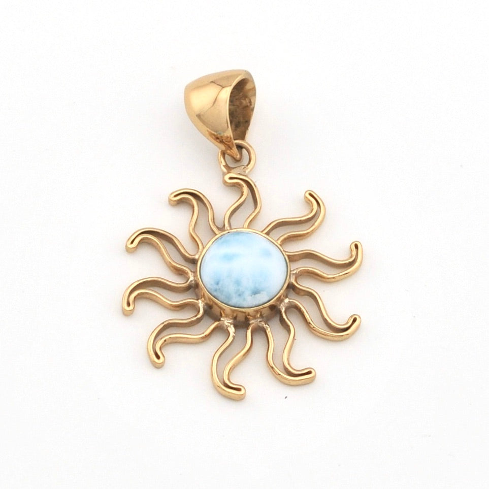 Gold sun-shaped pendant with a blue stone on a white background