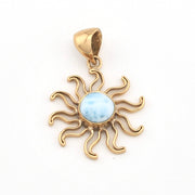 Gold sun-shaped pendant with a blue stone on a white background
