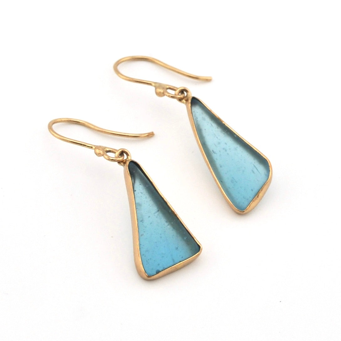 Pair of gold earrings with blue triangular stones on a white background