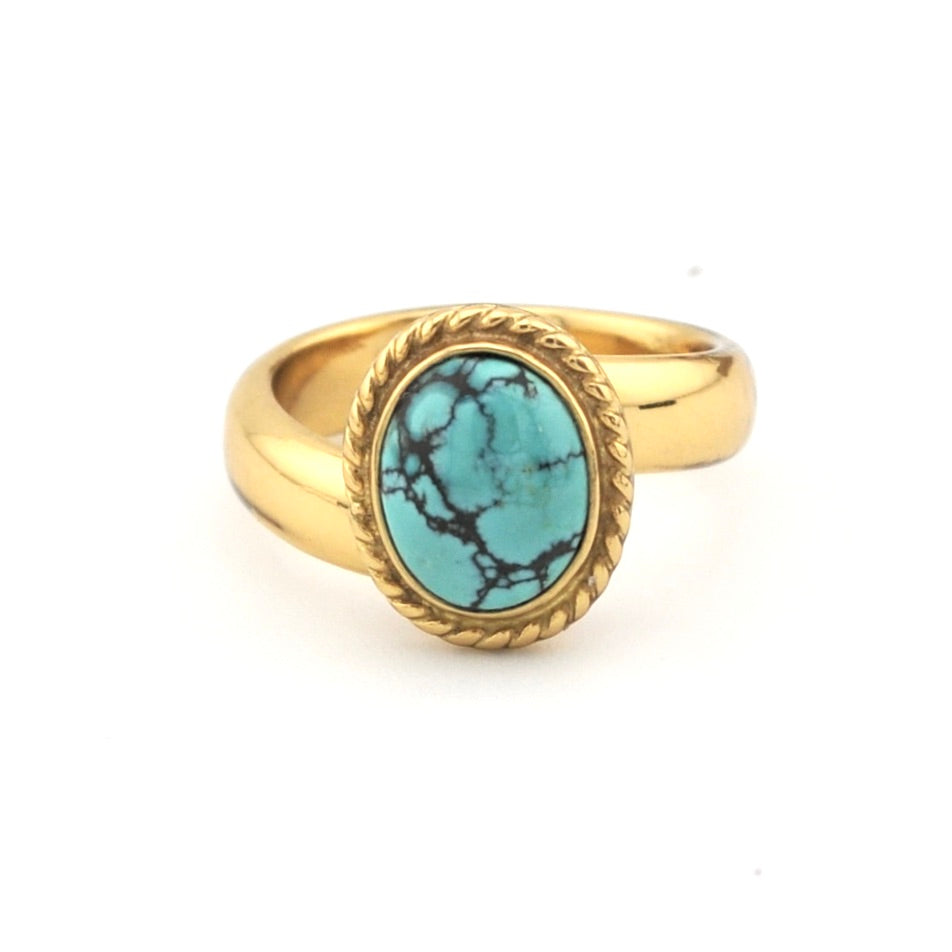Turquoise set in gold ring on white background