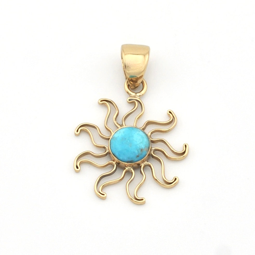 Gold sun-shaped pendant with a turquoise center on a white background