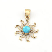 Gold sun-shaped pendant with a turquoise center on a white background