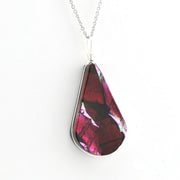 A teardrop-shaped pendant necklace featuring a dark red and magenta iridescent dichroic glass with silver metal borders and a silver chain, shown against a plain white background.