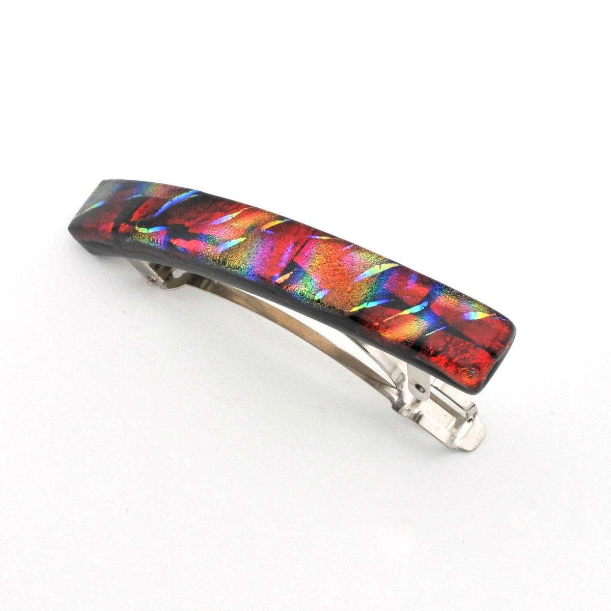 A hair barrette featuring a vibrant, iridescent glass top with a multicolor rainbow sheen over a black base, attached to a silver metal spring clasp, shown on a plain white background.