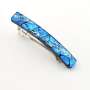 A rectangular hair barrette featuring a vibrant blue and silver metallic crackled glass design on the front, with a silver-toned metal spring mechanism visible underneath, set against a plain white background.