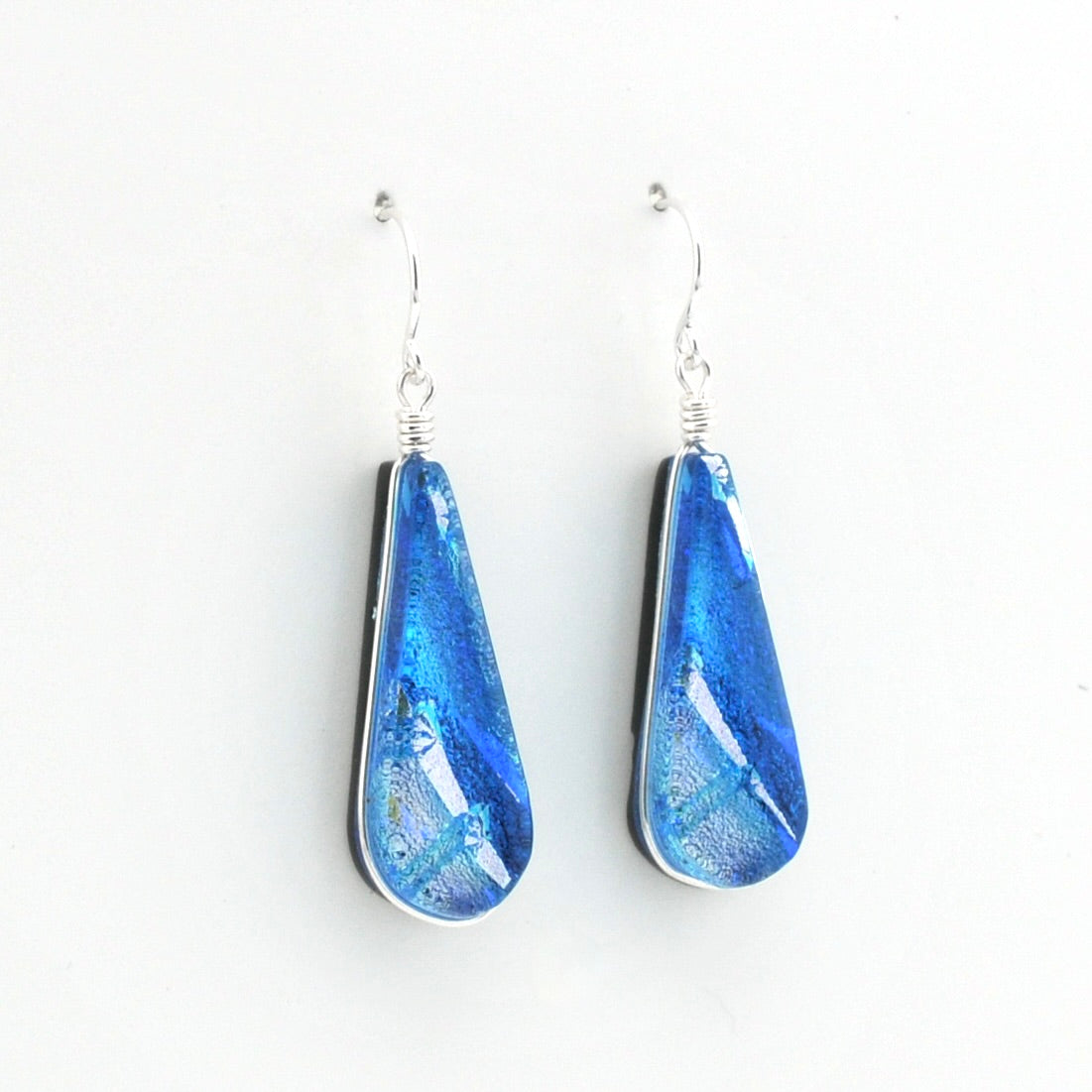A pair of teardrop-shaped blue glass drop earrings with silver fishhook wires, displayed against a clean white background.