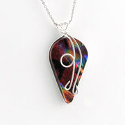 A silver necklace featuring a teardrop-shaped pendant made from an iridescent dichroic glass with a silver wire wrap design, shown on a plain white background.