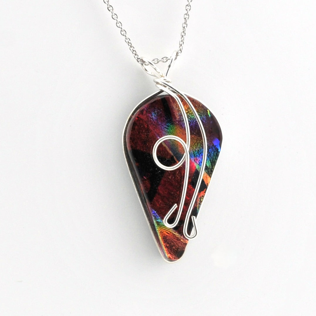 A silver necklace featuring a teardrop-shaped pendant made from an iridescent dichroic glass with a silver wire wrap design, shown on a plain white background.