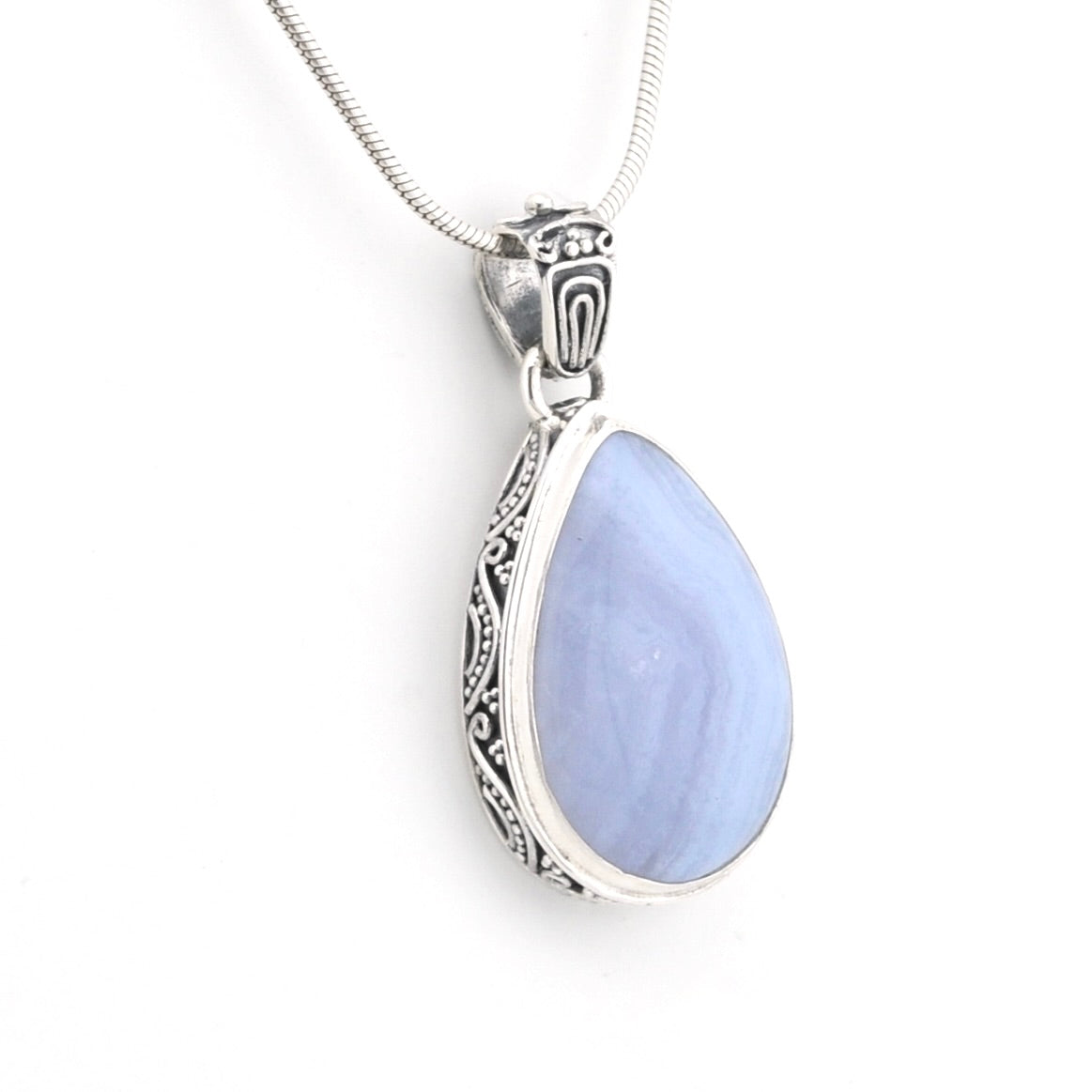 A silver teardrop pendant necklace featuring a smooth, light blue stone in an ornate silver bezel setting, suspended from a delicate silver snake chain against a plain white background.