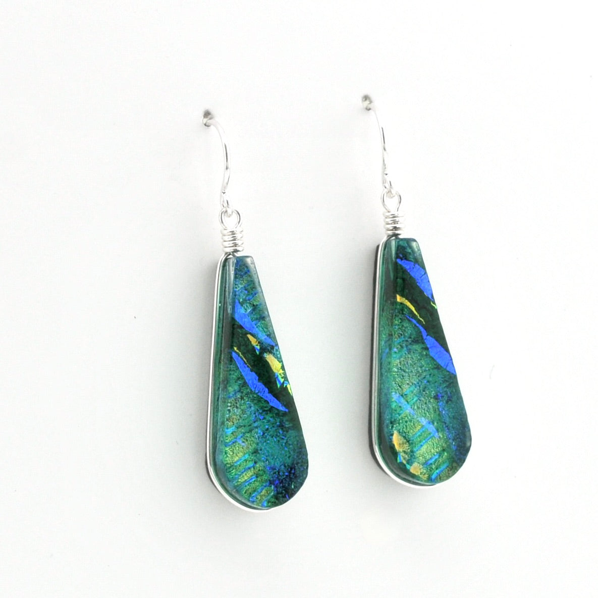 A pair of teardrop-shaped dangle earrings with silver fishhook wires and wrapped settings, featuring iridescent green, blue, and gold marbled glass pieces on a plain white background.