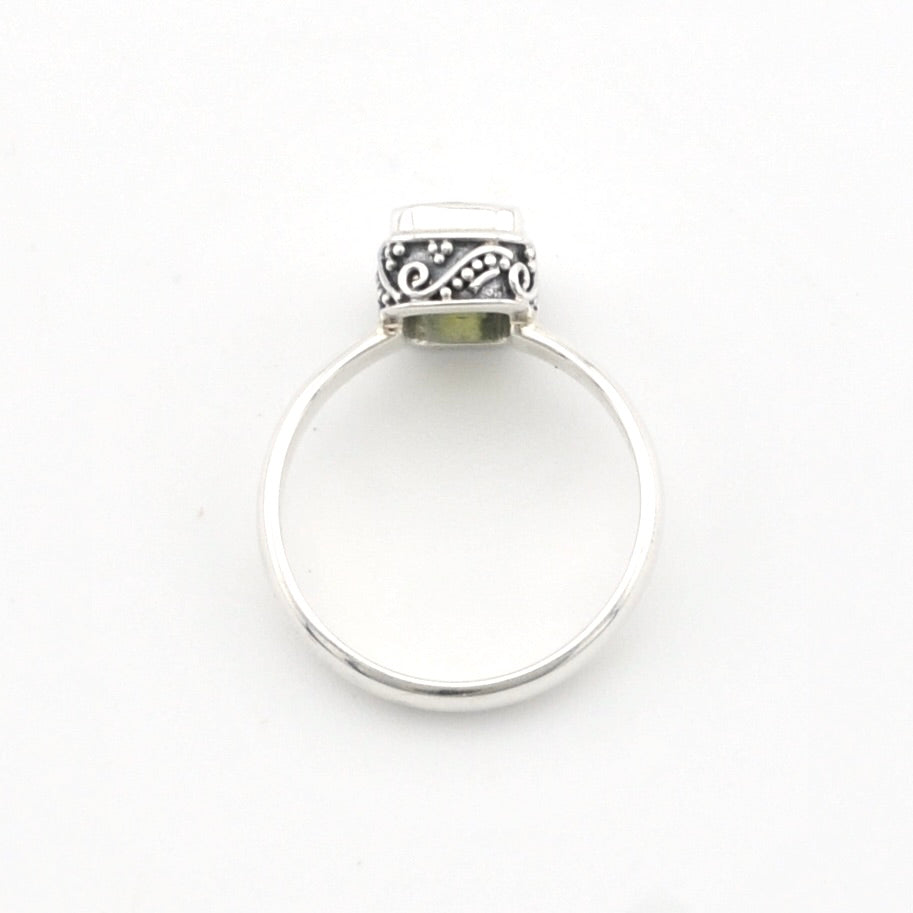 A sterling silver ring with a flat band and a decorative, oxidized scrollwork top setting, shown on a plain white background.
