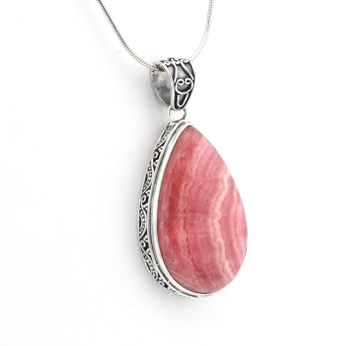 A teardrop-shaped pink stone pendant with natural banding, set in an ornate silver bezel and suspended from a silver chain against a white background.