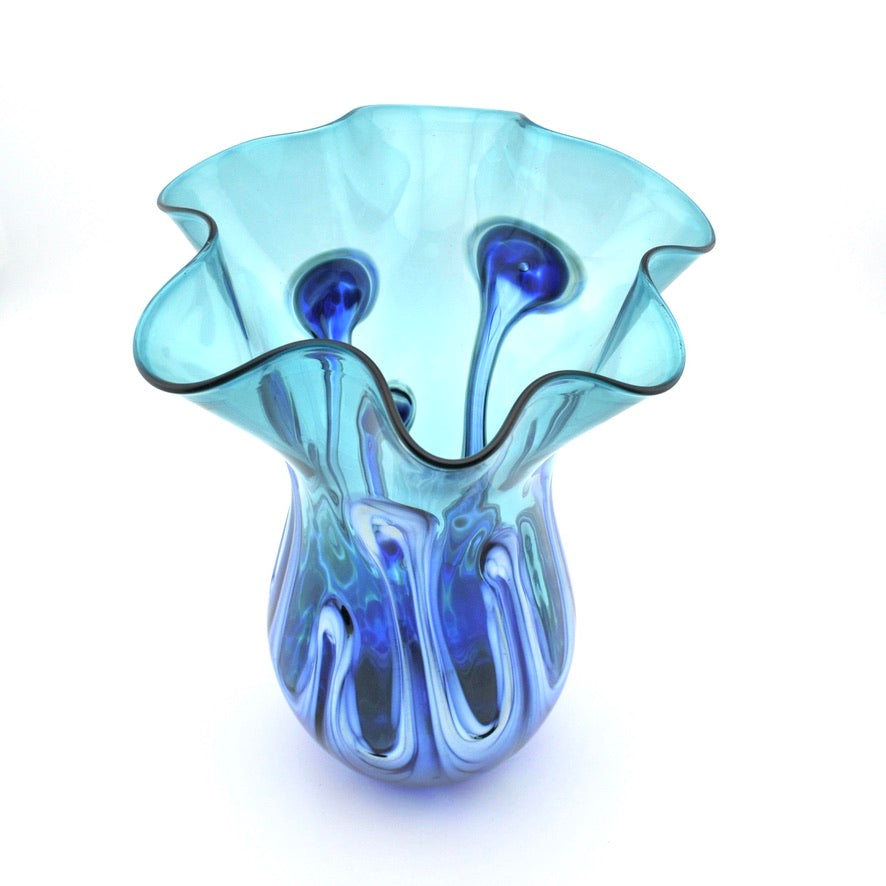 A hand-blown glass vase with a flared, ruffled rim and a bulbous base, featuring a color-shifting design that transitions from light aqua to deep cobalt blue, set against a plain white background.
