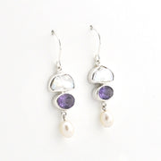 A pair of silver drop earrings featuring a white mother-of-pearl crescent, a purple amethyst oval, and a dangling white pearl, shown on a plain white background.