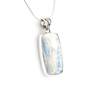 A silver rectangular pendant necklace featuring a polished blue and white marbled stone, suspended from a delicate silver chain against a plain white background.