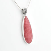 A silver pendant necklace featuring a teardrop-shaped pink stone, shown against a plain white background.