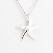 A polished silver starfish pendant necklace on a delicate silver chain, set against a clean white background.