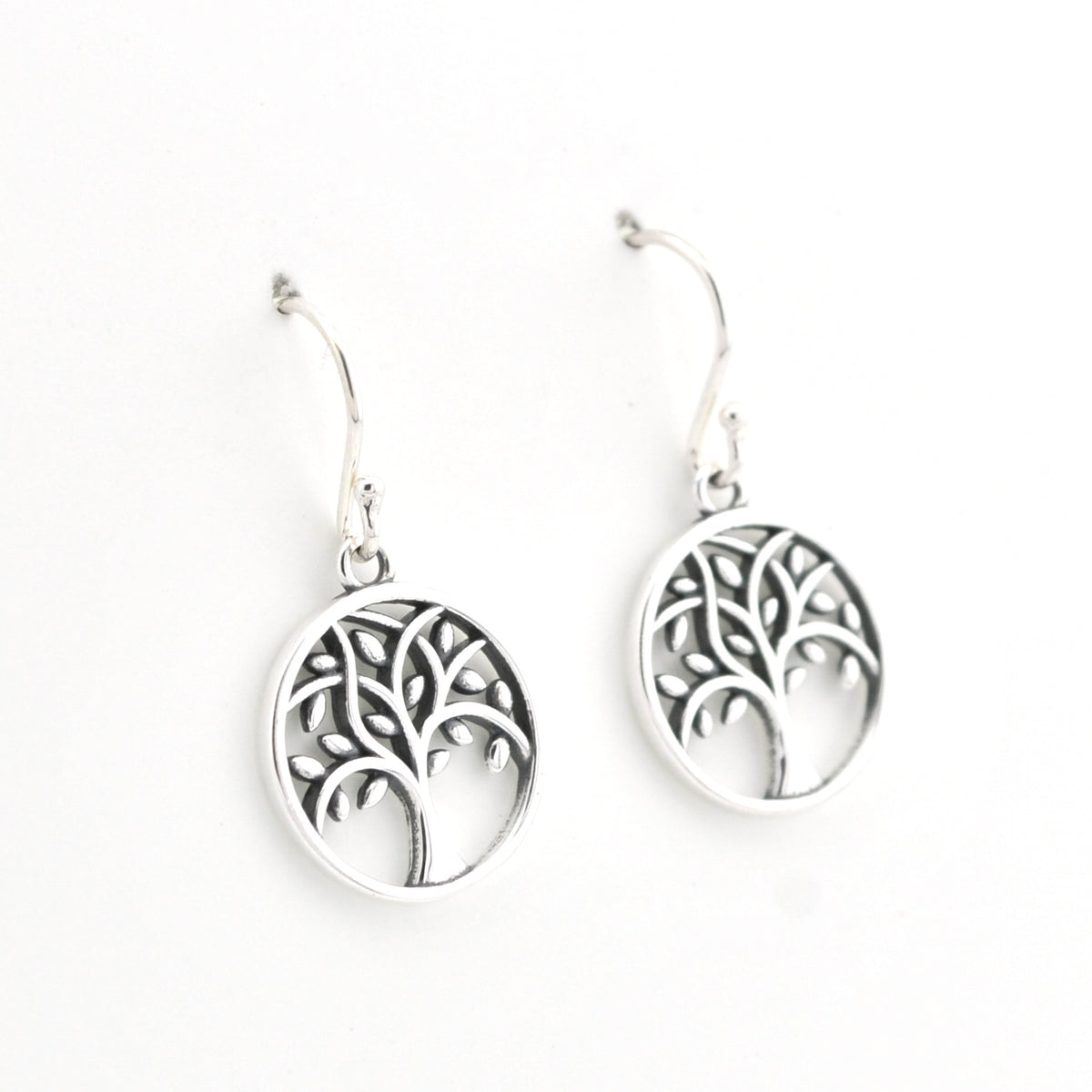 A pair of silver tree of life drop earrings with circular cutout pendants and fishhook wires, shown on a plain white background.
