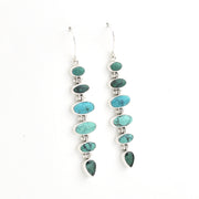 A pair of sterling silver dangle earrings featuring a vertical stack of oval and teardrop-shaped turquoise and green stone beads on a plain white background.