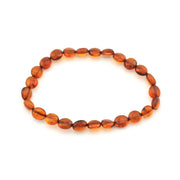 A beaded stretch bracelet made of smooth, polished oval amber beads in warm orange-brown tones, displayed on a clean white background.