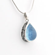 Teardrop-shaped blue pendant on a silver chain against a white background