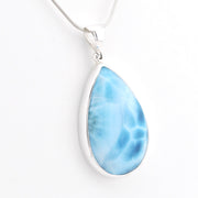 A teardrop-shaped Larimar pendant necklace in a silver bezel setting on a silver snake chain, shown against a plain white background.