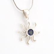 Silver sun-shaped pendant with a blue gemstone on a white background