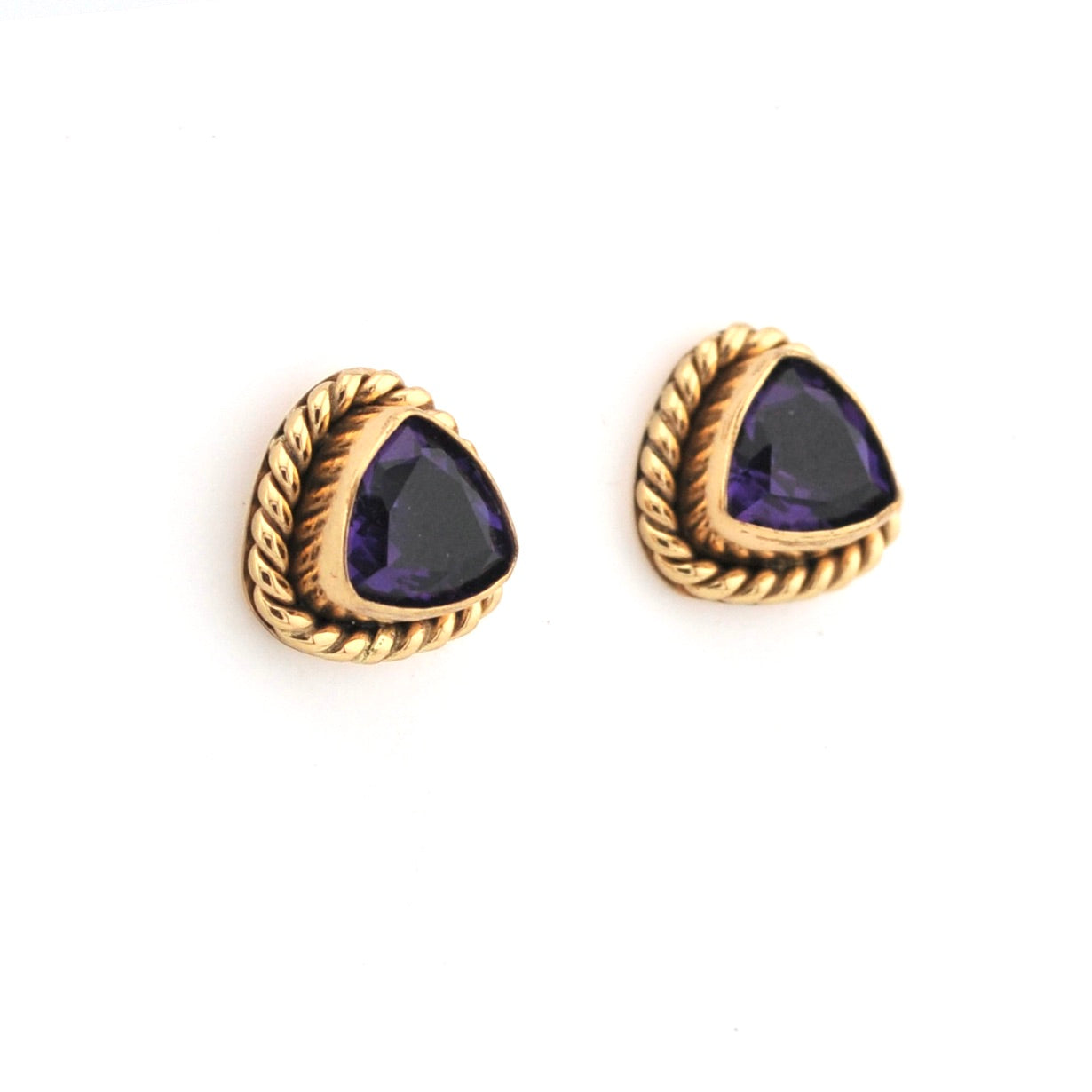 Pair of gold earrings with purple gemstones on a white background